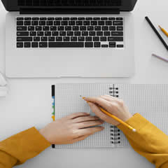 Laptop mit Stift und Schreibblock davor